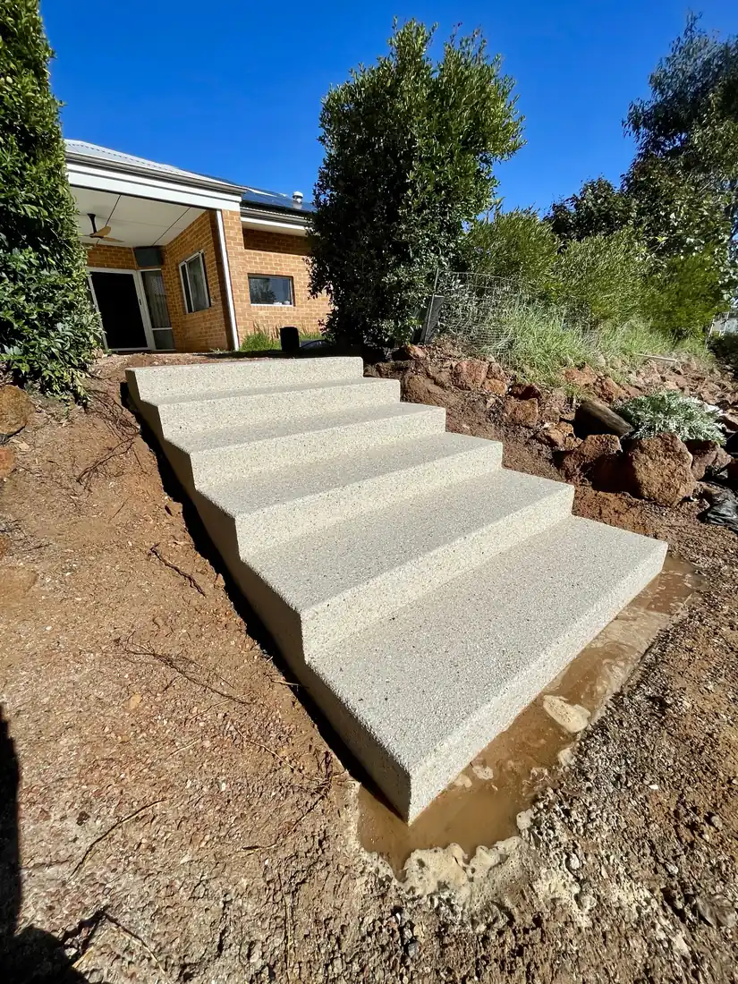 Freshly poured exposed aggregate stairs stepping up a sloped Perth yard