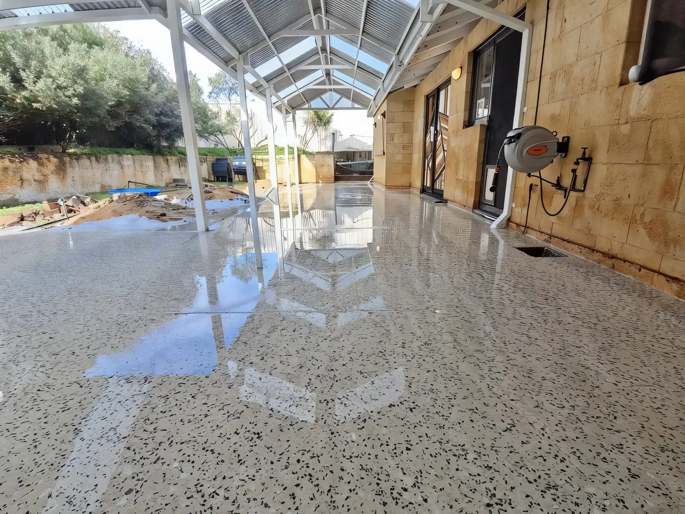 Sealed honed aggregate alfresco floor under a timber pergola, Perth