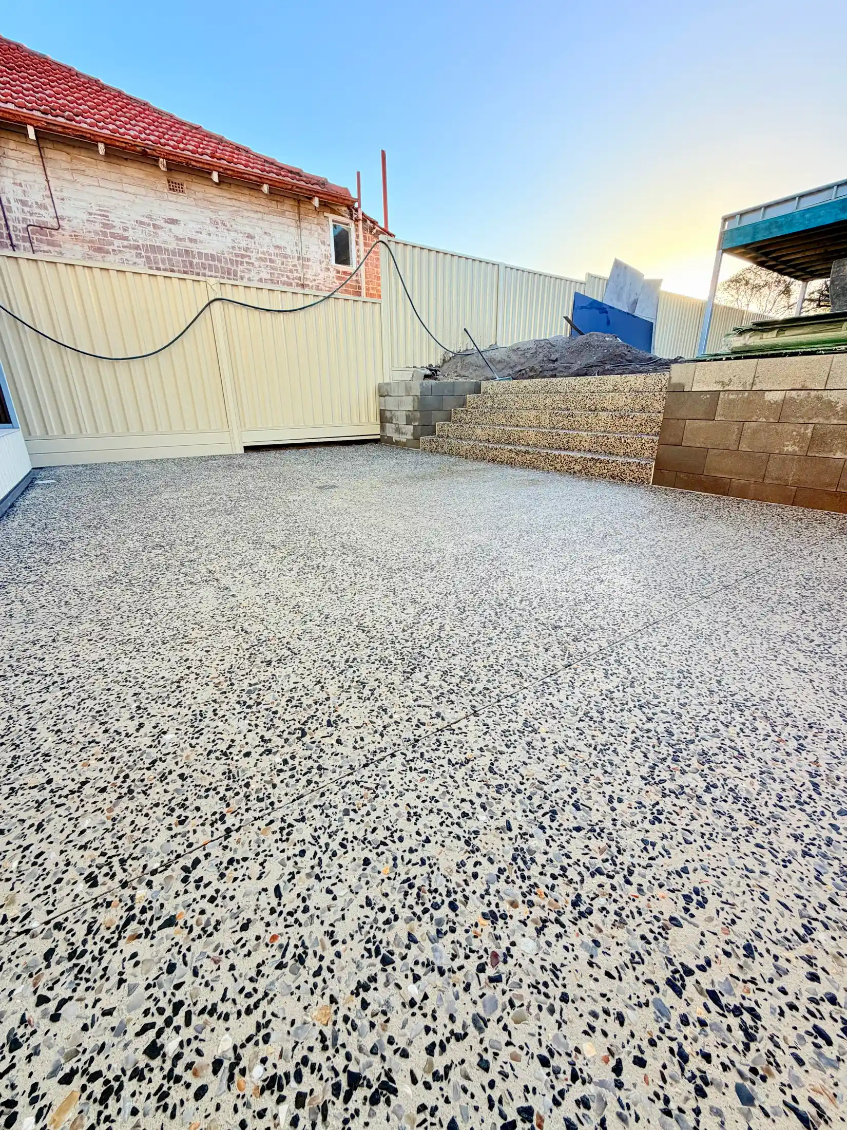 Charcoal exposed aggregate house surround along a Colorbond fence, Perth