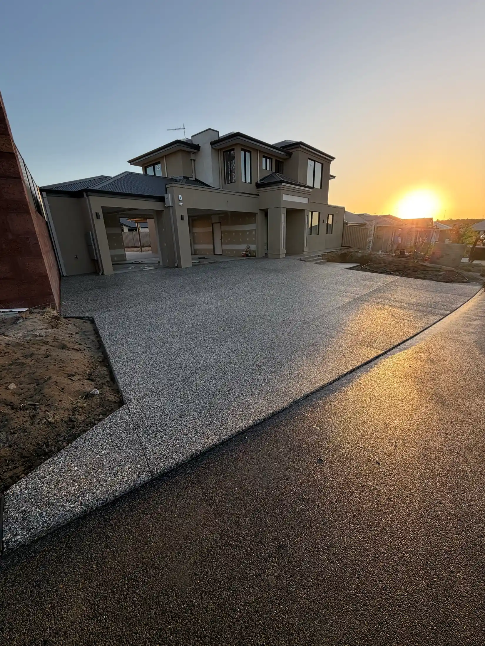 Exposed aggregate driveway at golden hour outside a modern two-storey Perth home