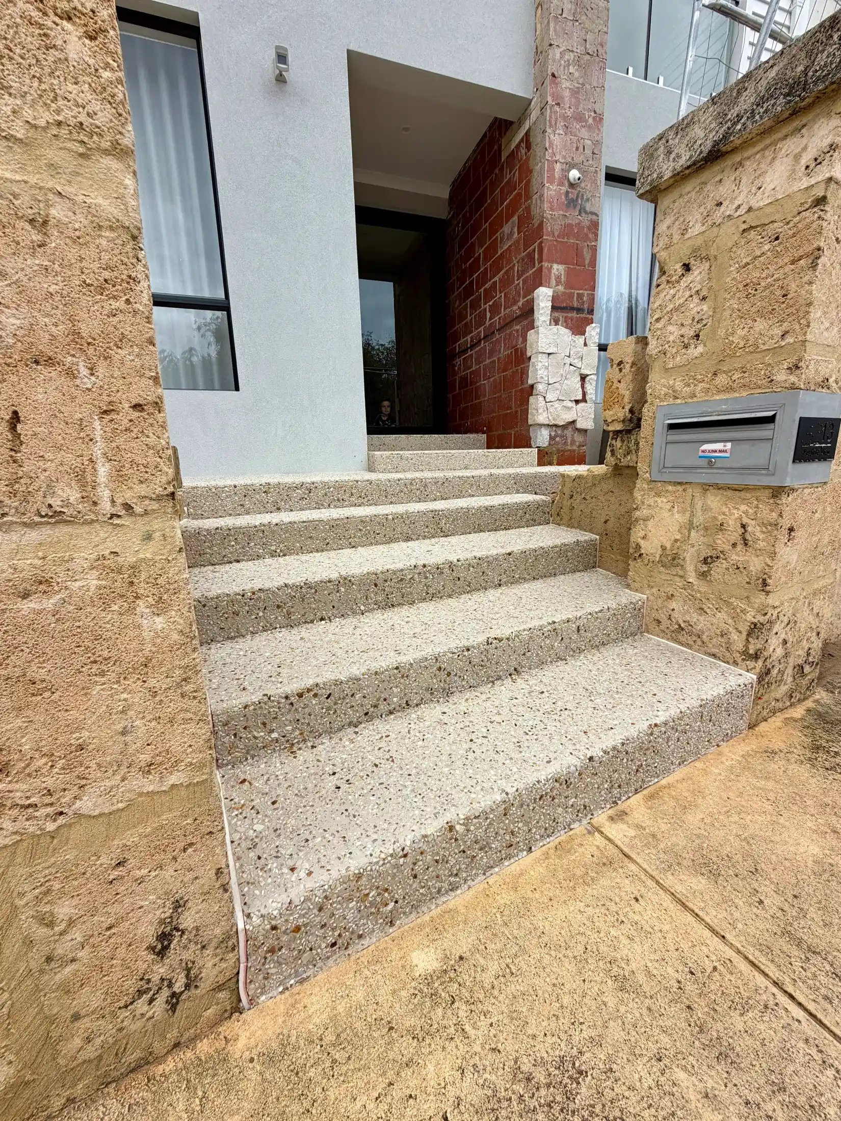 Exposed aggregate front entry steps against a rendered Perth home