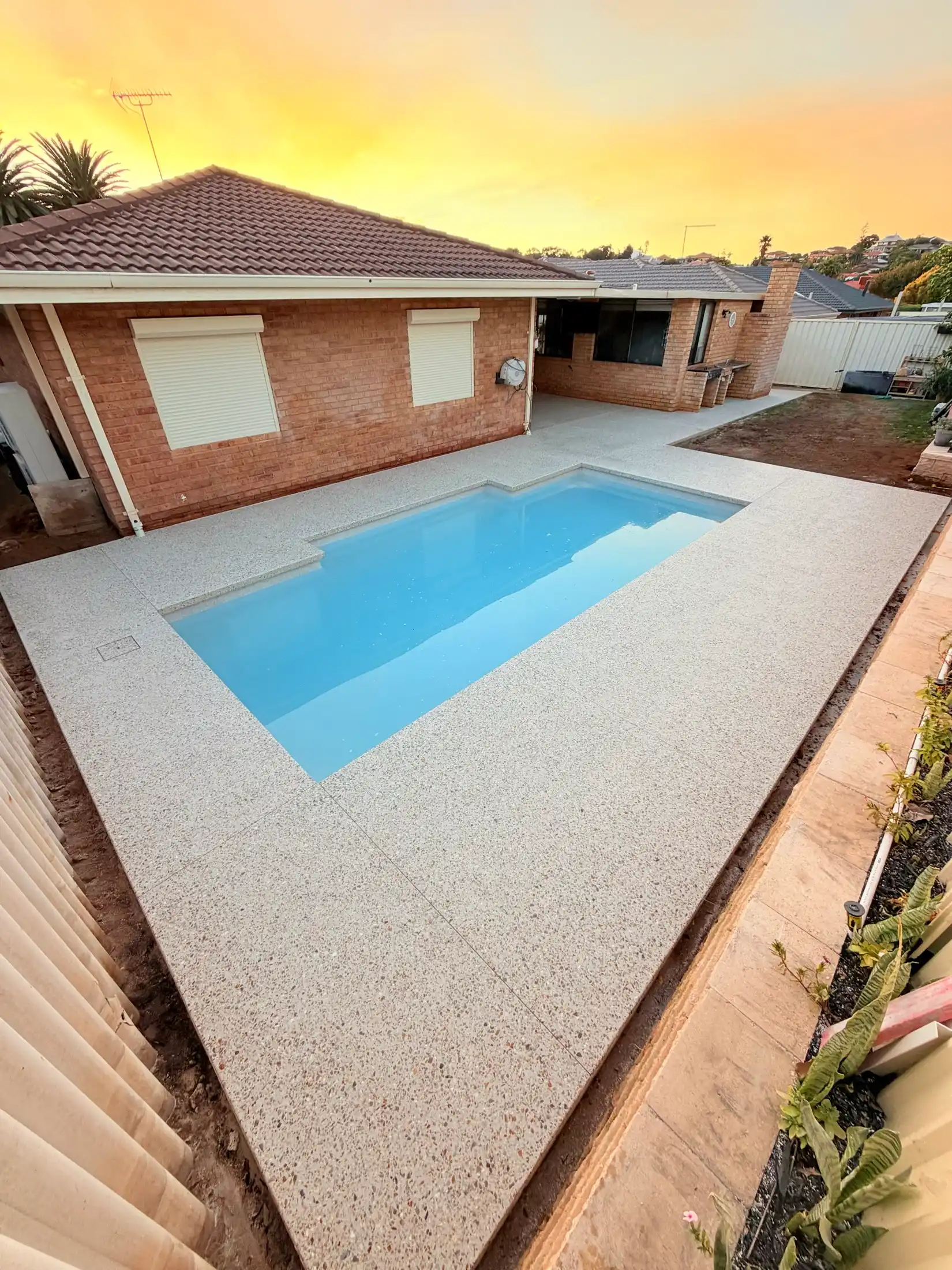 Exposed aggregate pool surround at golden hour, Perth backyard