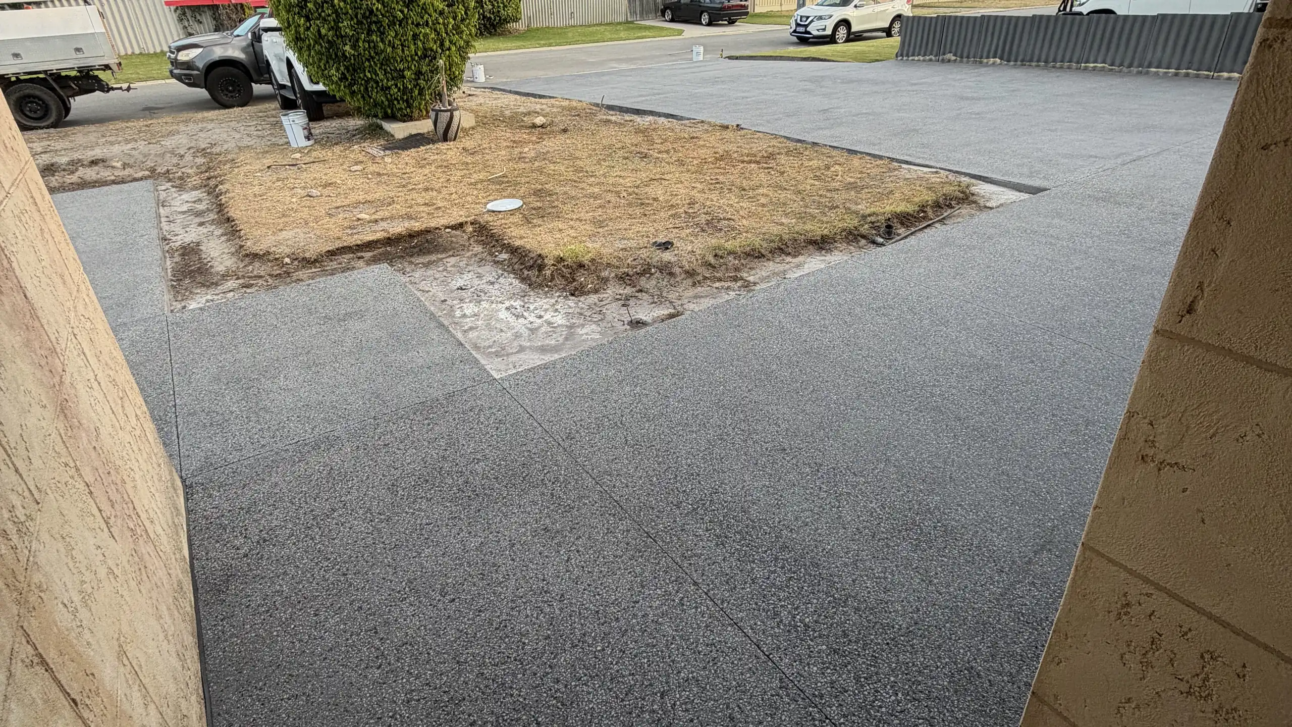 Charcoal exposed aggregate driveway running past a Perth home and workshop shed