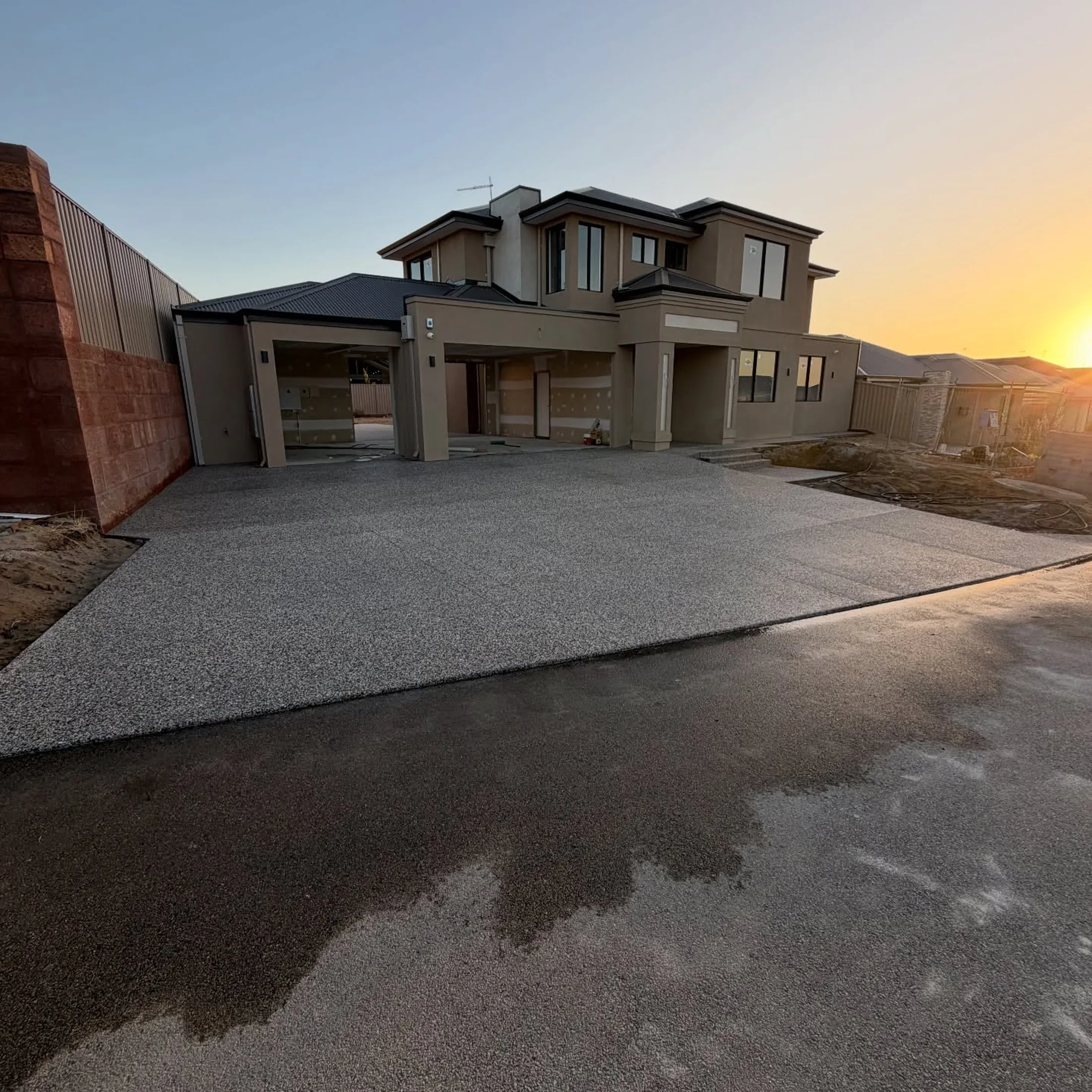 Exposed aggregate concrete driveway at dusk on a new two-storey Perth home by Only Concrete