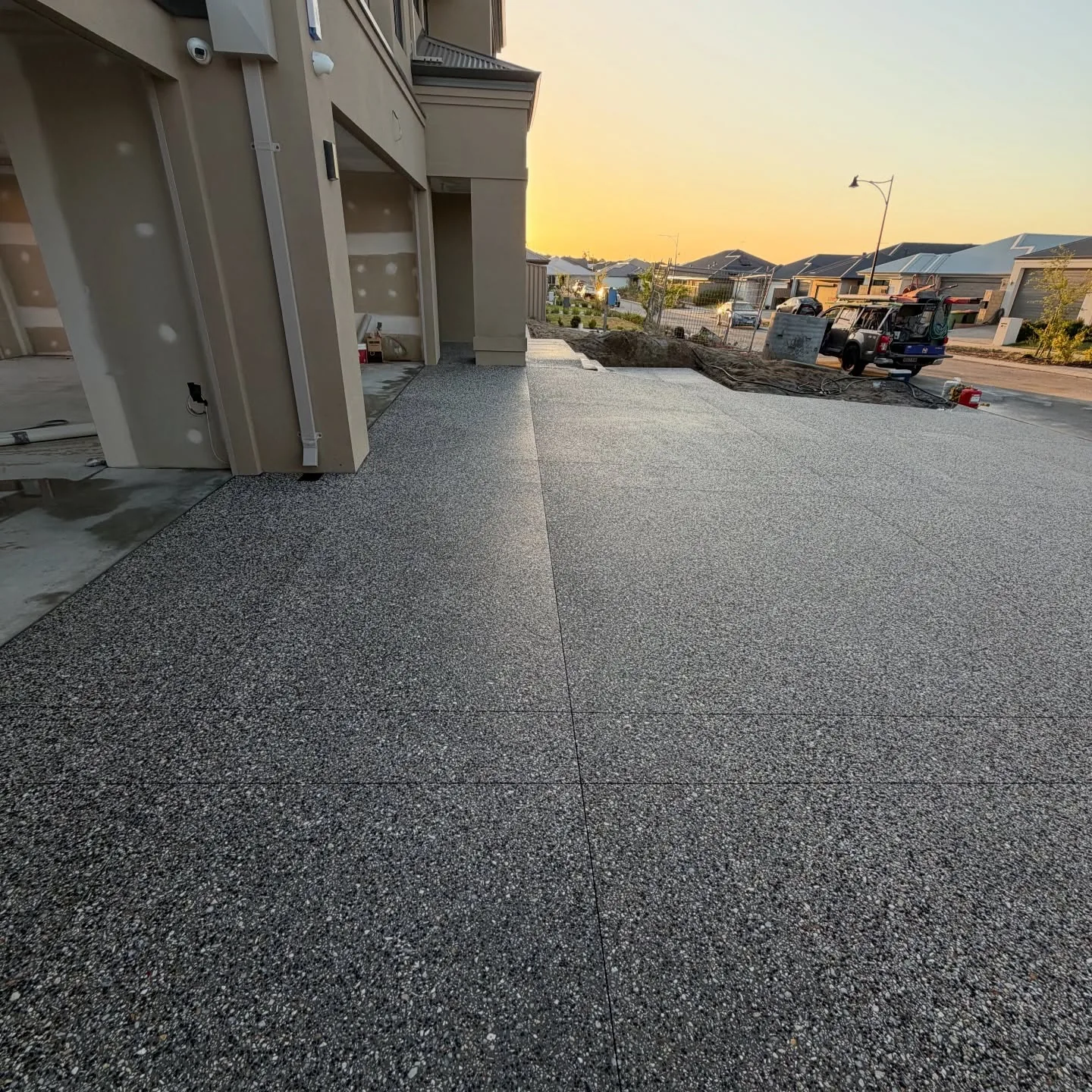 Wide exposed aggregate driveway at dusk on a new Perth home by Only Concrete